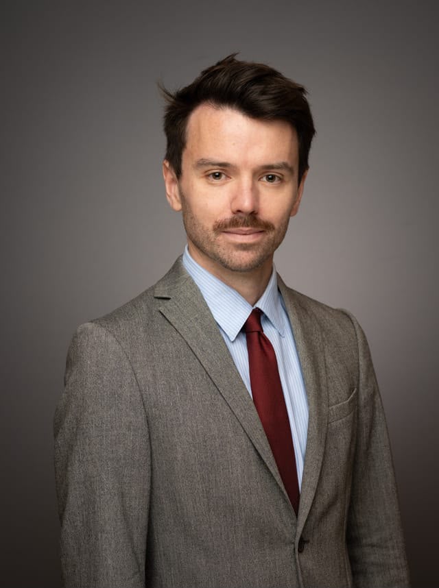Portrait officiel de Julien Capy, baryton-basse, en costume gris et cravate bordeaux